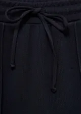 Pantalón de jogging azul marino de tejido fluido con cintura elástica ajustable con lazo, tiro medio, dos bolsillos laterales y costuras decorativas.
