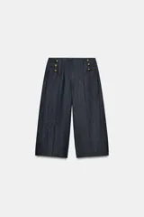 Bermuda larga de tiro alto en tejido de denim azul oscuro, con diseño de pernera recta y ancha, y detalles de botones metálicos dorados en la parte delantera.