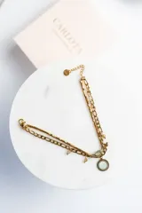 Pulsera dorada de acero quirúrgico con doble cadena, una de eslabones y otra de cuentas. Incluye dije circular con textura y cuentas colgantes en tonos neutros.