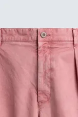 Pantalón relaxed fit color rosado, confeccionado en tejido de algodón con efecto lavado. Presenta pliegues frontales, bolsillos delanteros y bolsillos traseros de vivo. Cierre frontal con cremallera y botón.