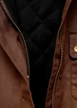 Parka de estilo encerado en color marrón, con diseño recto, cuello camisero de pana en contraste, cierre frontal con cremallera y botones, y múltiples bolsillos de parche con solapa.