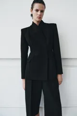 Blazer entallada color negro de ZARA Woman Collection, con escote en pico, manga larga con hombreras, bolsillos con solapa en el delantero y cierre frontal con botones ocultos.