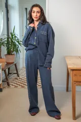 Camisa de denim negra con botones metálicos dorados y bolsillos con tachas doradas. De corte amplio.