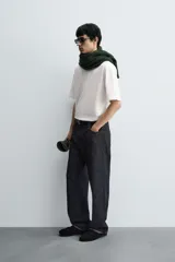 Camiseta blanca de corte holgado, cuello redondo y manga corta. Presenta un parche bordado en la espalda con diseño a contraste.