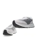 Championes New Balance modelo U370, de estilo retro y perfil bajo. Presentan un diseño en tonos grises, combinando paneles de malla textil con refuerzos de gamuza. Incluyen el logo característico en los laterales, cierre mediante cordones y una suela de goma con entresuela blanca.