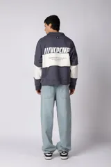 Buzo tipo polo de calce relajado con diseño de bloques de color en tonos marrón y blanco. Presenta cuello polo, cierre frontal parcial y logo estampado en el pecho. Confeccionado en tejido pesado con estructura.