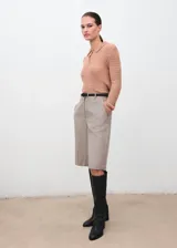Polo de tejido de punto calado con cuello clásico y cierre frontal de botones. Presenta un diseño recto de manga larga.