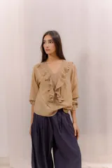 Camisa blanca de algodón con escote en V, volados delanteros con detalles de encaje y mangas largas con puños fruncidos.
