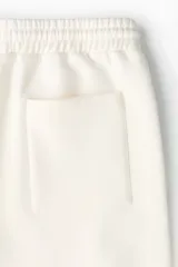 Short de felpa color beige de la marca Lotto, con cintura elástica con cordón de ajuste, bolsillos laterales y franjas laterales estampadas con el logo de la marca.