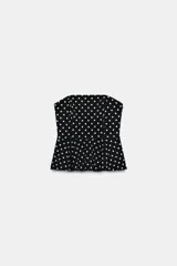 Top de escote recto y hombros descubiertos, color negro con estampado de lunares blancos. Presenta diseño entallado con bajo acabado en peplum y cierre lateral con cremallera oculta.