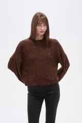 Polera de punto color marrón con destellos brillantes, cuello redondo, mangas largas abullonadas y diseño holgado.