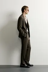 Blazer slim fit de corte sastrero en color verde oscuro, con cuello de solapa de muesca, bolsillos con solapa en la cadera y cierre frontal de botones.