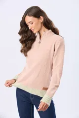 Buzo tejido combinado de color beige, con cuello alto, medio cierre metálico y puños y ruedo acanalados en tono tostado.