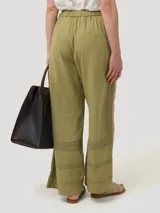 Pantalón de lino orgánico y viscosa color crema, de tiro alto y corte recto, con pinzas delanteras, bolsillos laterales y detalle de trabilla ajustable con hebilla metálica en la cintura.