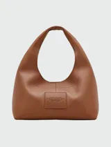 Bolso tipo saco de cuero color camel, con correa ancha para llevar al hombro. Presenta el logo de la marca grabado en relieve en el frente.