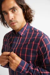 Camisa de manga larga con cuello clásico y cierre frontal abotonado. Presenta un estampado de cuadros en tonos azul marino y rojo. Confeccionada en algodón, cuenta con un corte slim fit y logo bordado en el pecho.