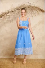 Conjunto de crop top con tirantes y pollera midi, color celeste, confeccionado en lino con detalles de bordado floral blanco.