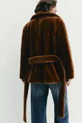 Chaqueta de textura efecto pelo en color marrón, con cuello de solapa, manga larga y cierre frontal cruzado mediante cinturón del mismo tejido. Cuenta con bolsillos delanteros.