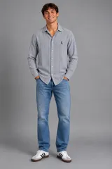 Camisa de manga larga color gris con diseño de rayas verticales sutiles, cuello italiano y cierre frontal con botones. Cuenta con un pequeño bordado en el pecho.