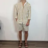 Camisa de lino de corte oversize con diseño de rayas verticales en tonos blanco y tostado, manga larga y cierre frontal con botones.