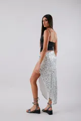 Falda midi plateada de lentejuelas, con tajo lateral y nudo en la cintura.