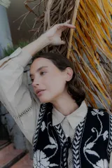 Chaleco tejido de punto con diseño floral en contraste, cierre frontal con lazos y terminaciones con guardas geométricas.