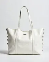 Cartera tipo tote de símil cuero blanco, con dos asas de mano y detalles de herrajes plateados en los laterales.