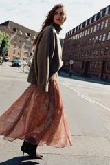 Falda midi de corte fluido con estampado paisley en tonos naranja, rosado y beige. Presenta cintura elástica y viene acompañada de un cinturón de cuero sintético marrón con hebilla metálica. Incluye forro interior.