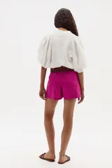 Short de lino color fucsia con cintura alta y cinturón de cuero trenzado marrón.