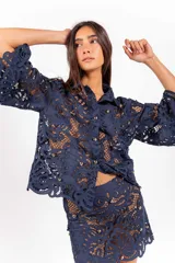Camisa de molde clásico confeccionada en encaje bordado tipo guipur, color azul, con mangas largas amplias y aplicación de tachas doradas.