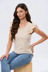 Remera de algodón color beige, de manga corta con volados de broderie, escote redondo y cuerpo liso.
