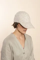 Gorra con visera confeccionada en lana fina sin teñir, con un sutil patrón de tejido en espiga.