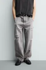 Pantalón de jean estilo carpintero con corte relaxed fit, tiro medio y pierna recta. Presenta un lavado azul medio con efecto desgastado y roturas en las rodillas. Incluye bolsillos laterales tipo plastrón, tira multifunción en la pierna, cierre frontal con cremallera y botón.