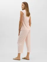 Pijama compuesto por remera sin mangas con escote redondo, botones frontales y detalle de puntilla, acompañado de un pantalón capri con cintura elástica. Presenta un estampado floral en tonos rosados sobre base gris.