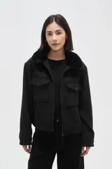 Chaqueta negra de corte holgado con cierre frontal, cuello camisero con detalle de corderito y bolsillos frontales con solapa y botones.