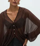 Blusa de poliamida con estampado geométrico, diseño amplio y fluido, escote en V con cierre frontal de botones, mangas largas abullonadas con puños ajustados y acabado con sutil transparencia.