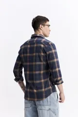 Camisa de manga larga confeccionada en viyela de algodón con diseño de cuadros en tonos azul y verde. Presenta cierre frontal con botones, cuello clásico y bolsillo en el pecho.