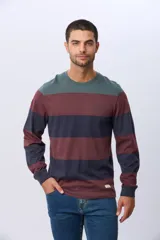 Remera de manga larga con diseño de rayas horizontales en tonos azul marino, beige y verde oscuro. Presenta cuello redondo y una pequeña estampa tipográfica en el pecho, además de una etiqueta decorativa en el ruedo.