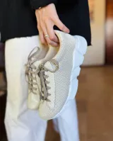 Championes urbanos de mujer con diseño de malla texturizada en color negro y detalle metálico en tono dorado en el talón. Poseen una suela gruesa y resistente, ideal para uso diario.