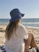 Gorro bucket reversible de jean elastizado con pespuntes en rojo. Un lado es de tono oscuro y el otro claro.