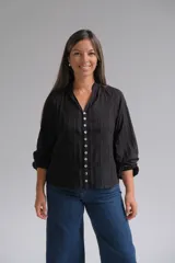 Blusa negra de manga larga con cierre frontal de botones, cuello mao y textura sutilmente rayada con detalles bordados.