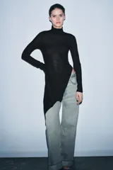 Top negro de manga larga con cuello perkins y bajo asimétrico con drapeado lateral.