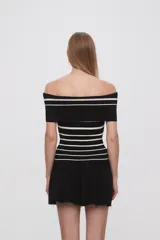 Top negro de tejido de punto con escote off-shoulder y rayas horizontales blancas.