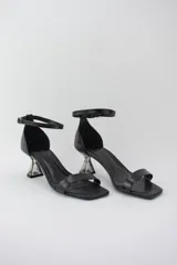Sandalias negras con punta cuadrada, tira delantera fina y pulsera ajustable al tobillo. Destacan por su taco geométrico transparente de altura media.