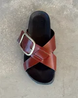 Sandalias marrones de cuero con tiras cruzadas y hebilla metálica.