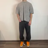 Remera gris con efecto gastado, corte boxy y estampado ovalado en la espalda.