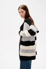 Saco de punto con diseño de rayas horizontales en negro, gris y blanco. Presenta cuello en V, cierre frontal con botones y bolsillos laterales.