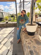 Sweater verde tejido con cuello redondo y diseño de cabeza de vaca en cuero marrón con bordados a mano en color beige.