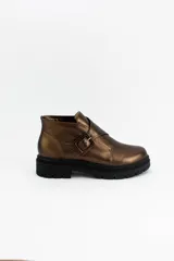 Botín de cuero metalizado en tono bronce, con diseño de hebilla lateral decorativa y suela track negra de goma.