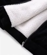 Campera de pana negra con cuello de sherpa blanco, cierre frontal por cremallera y bolsillos delanteros con solapa y botón. Presenta forro interno de sherpa para mayor calidez.